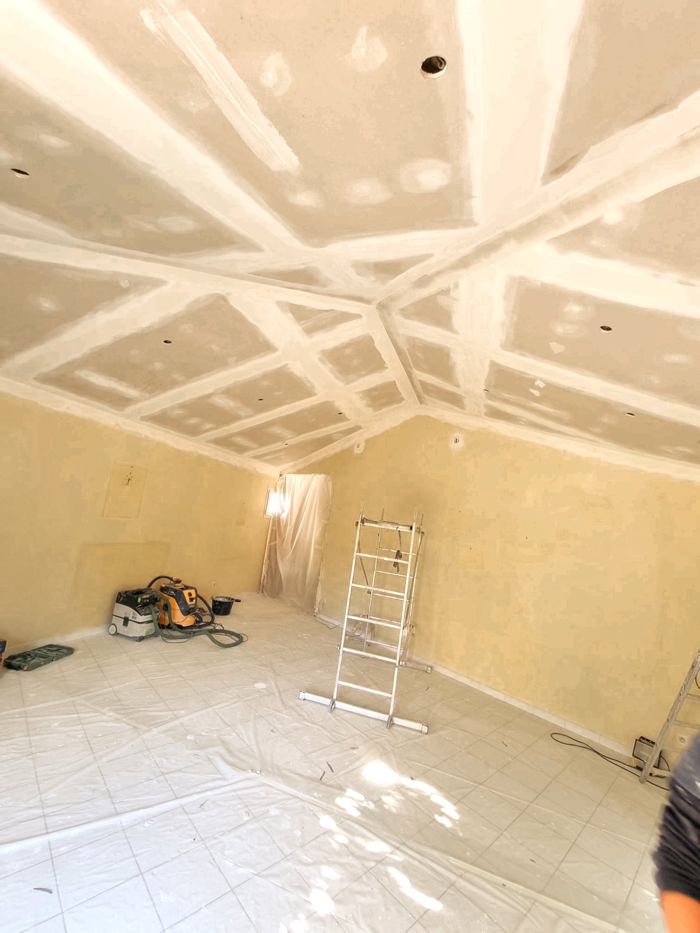 Plafond en plaques de plâtre dont les joints de bande ont été tirés et poncés, sur un chantier de Forcé Rénov'